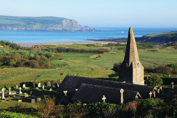St Enodoc Church overlooking St Enodoc golf course and the sea beyond, Rock, Cornwall. John Betjeman lies buried in the graveyard