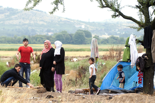 Migrants warm up beside a campfire on the Macedonian-Greek border (Photo Robert Atanasovski/Getty)