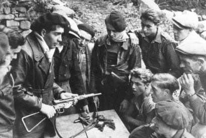 Members of the Maquis study the mechanism and maintenance of weapons dropped by parachute in the Haute-Loire