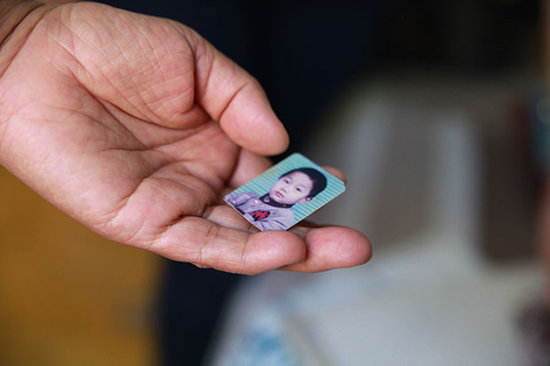 Small comfort: a mother, whose only son was killed in a car accident at the age of 23, holds a picture of him as a child. Many such bereaved parents, unable to conceive again and struggling to support themselves in later life, say they have nothing left to live for