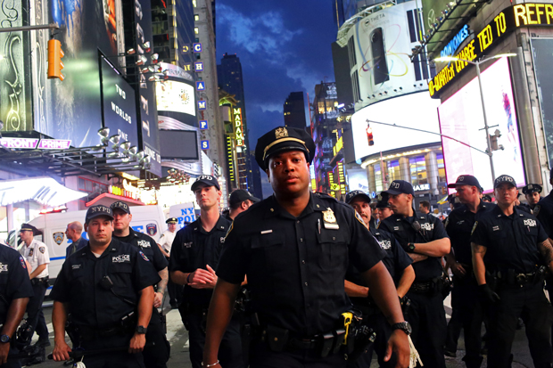 Police watch activists protest in Times Square in response to the recent fatal shootings (Photo: Getty)