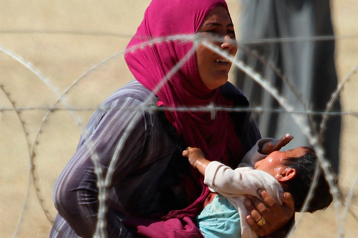 A mother and child, refugees from Raqqa, wait to cross into Turkey in September 2014