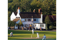 A game of cricket on Tilford Green, Surrey, outside The Barley Mow
