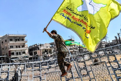 A member of the Syrian Democratic Forces holds up the group's flag (Getty)