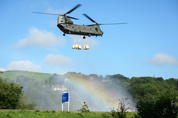 A Chinook helicopter prepares to drop sandbags onto the dam wall at the Toddbrook reservoir last week (Getty)