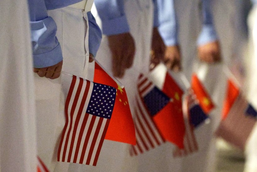 BEIJING, CHINA - MAY 13: Chinese youth hold American and Chinese flags as they join officials to welcome U.S. President Donald Trump at Beijing Capital International Airport on May 13, 2026 in Beijing, China. President Trump is meeting with President Xi Jinping in Beijing to address the Iran conflict, trade imbalances, and the Taiwan situation while establishing new bilateral boards for economic and AI oversight. (Photo by Alex Wong/Getty Images)